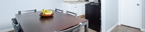 A dining room with a wooden table and chairs and a painting on the wall.