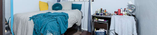 A bedroom with a bed, desk, and chair.