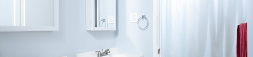A white bathroom with a sink, mirror, toilet, and shower.