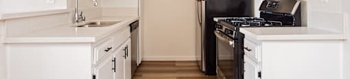 A kitchen with white cabinets and black appliances.