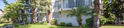 an apartment building with a lawn and trees in front of it