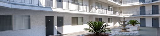 a courtyard with a fountain and a white building with black doors