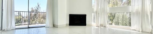A spacious room with a flat-screen TV and large windows.