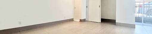 A spacious room with a tiled floor and a door on the right.