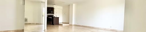 A spacious room with marble tiled flooring and white walls.