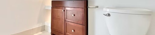 A white toilet sits next to a wooden cabinet in a bathroom.