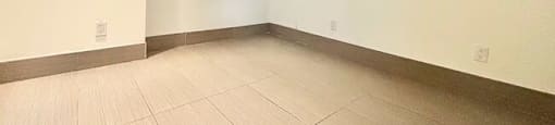 A room with white walls and a light brown floor.
