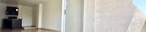 A room with a sliding glass door and a grey carpet.
