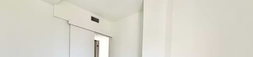 A white room with a closed door and a tiled floor.