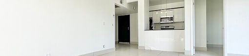 A spacious room with white walls and floor tiles.