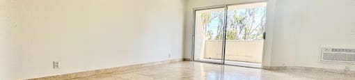 Empty room with tiled floor and sliding glass door.