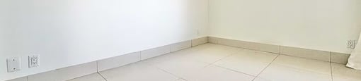 A white tiled room with a white wall and a white tile floor.