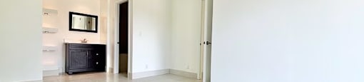 A spacious room with white walls and floor tiles.