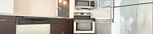 A kitchen with a refrigerator, oven, microwave, and sink.