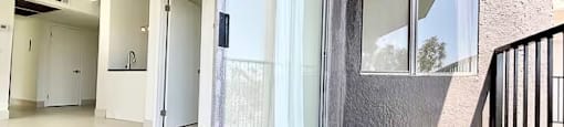 A balcony with a glass door leading to a hallway.