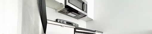 A modern kitchen with a stainless steel refrigerator, microwave, and oven.