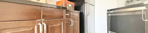 A kitchen with brown cabinets and a black refrigerator.