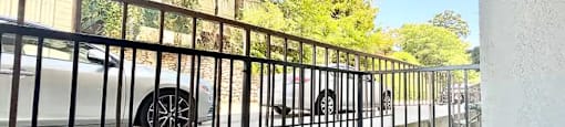 A black metal fence with a white car behind it.