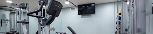 a gym with exercise machines and a tv on the wall