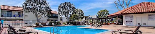 a swimming pool with lounge chairs and a building in the background