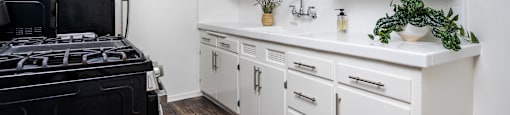 a kitchen with white cabinets and a black stove