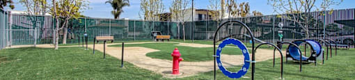 a fire hydrant in the middle of a grassy area with a chain link fence in