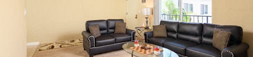 a living room with leather couches and a glass coffee table