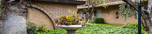a fountain sits in the middle of a grassy area in front of a building