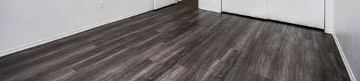 a bedroom with white walls and wood flooring and a closet