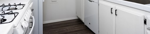 an empty kitchen with white cabinets and a white stove and refrigerator