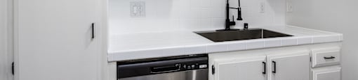 an empty kitchen with white cabinets and a sink