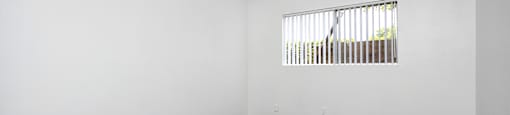 an empty room with white walls and wood floors and a window