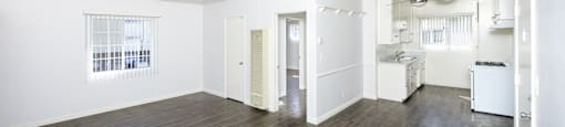 an empty living room and kitchen with white walls and wood floors