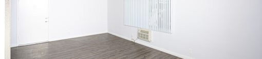 an empty room with white walls and wood floors