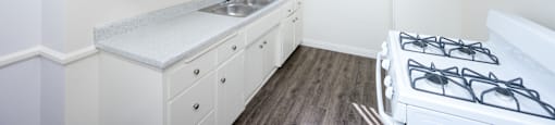 a kitchen with white cabinets and a sink and a stove