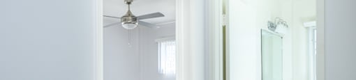 an empty bathroom with a mirror and a ceiling fan