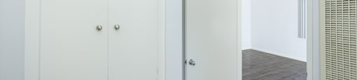 a bedroom with white cabinets and a door to a closet