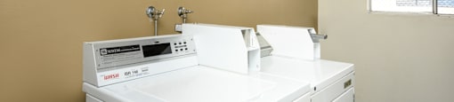 a laundry room with two washing machines and a window