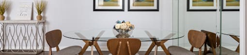 a dining room with a glass table and chairs and a ceiling fan