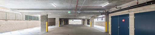 A long, empty parking garage with a red hose running along the ceiling.
