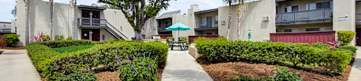 an umbrella sits in the middle of a garden at the whispering winds apartments in pearland,