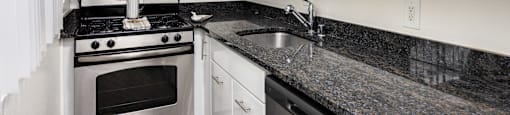 a kitchen with white cabinets and granite counter tops and stainless steel appliances