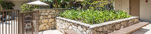 a stone retaining wall with a wooden bench in front of an apartment building