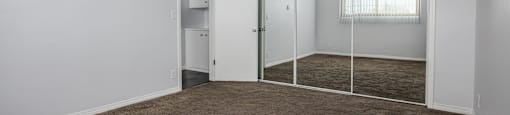 an empty room with carpet and a mirrored closet