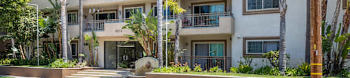 a white apartment building with palm trees in front of it