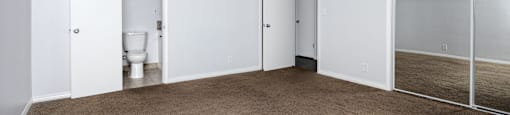 an empty living room with a toilet and sliding glass doors