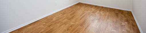 the spacious living room of an apartment with wood flooring and a window