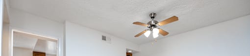 the living room and dining room of an empty house with a ceiling fan
