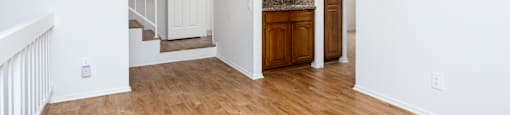 the living room and entryway of an empty house with wood floors and white walls