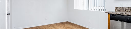 an empty living room with a ceiling fan and a kitchen